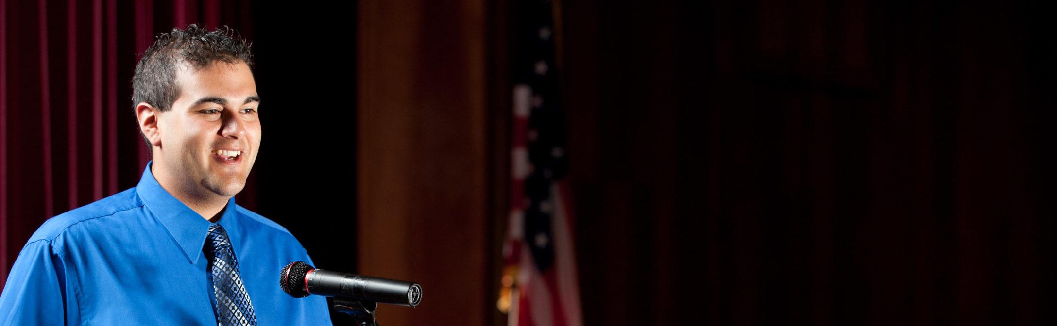 Man speaking on stage at a podium