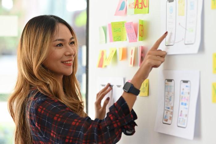 A female student pointing to something on a white board and explaining it.